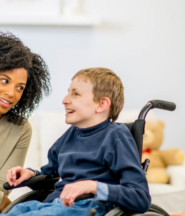 Carer and child in wheelchair talking and smiling